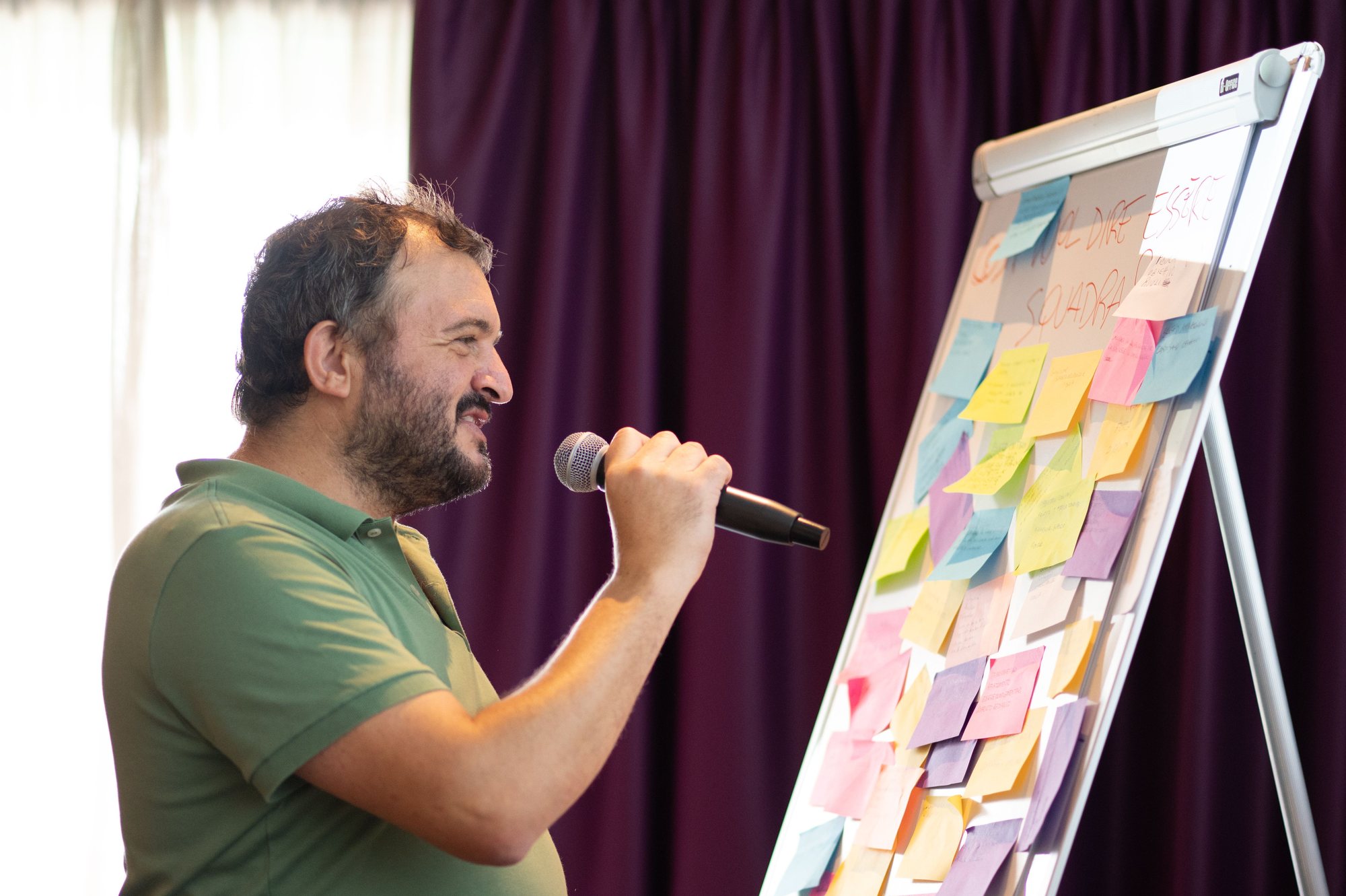 Loris Dal Poz al microfono davanti a una lavagna piena di post-it