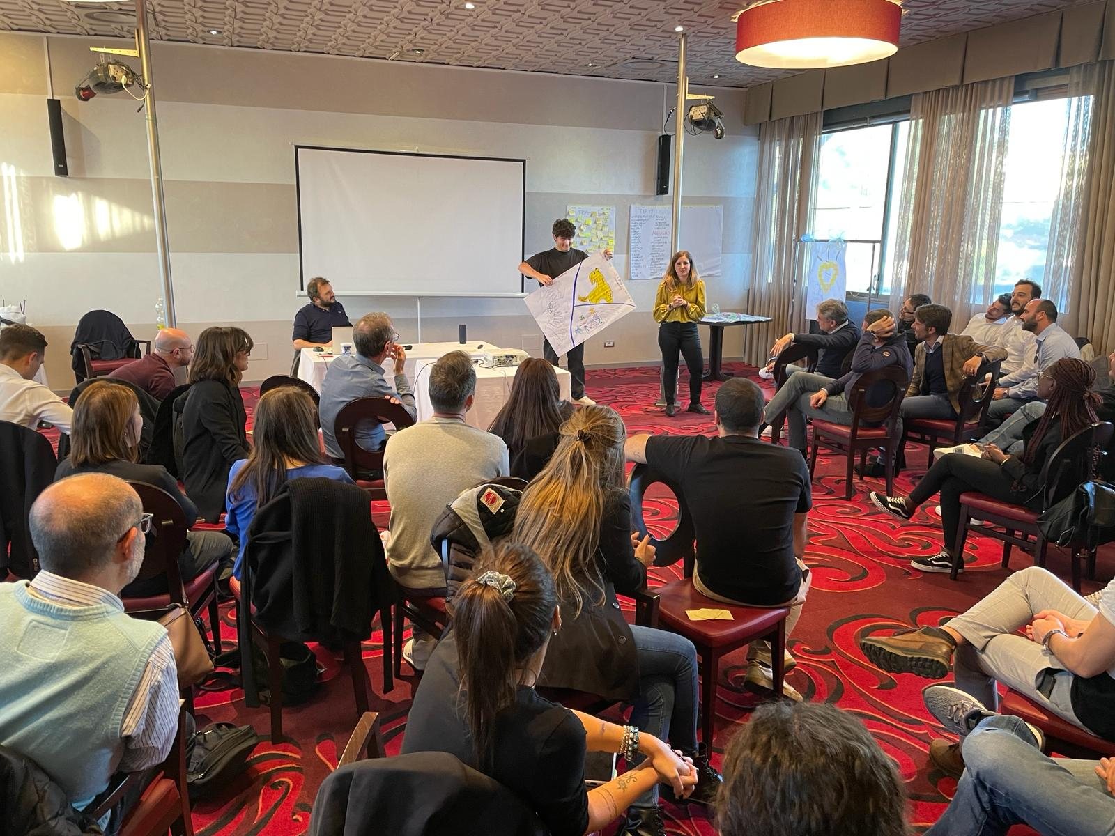 Un gruppo in cerchio ascolta la presentazione di un lavoro di squadra